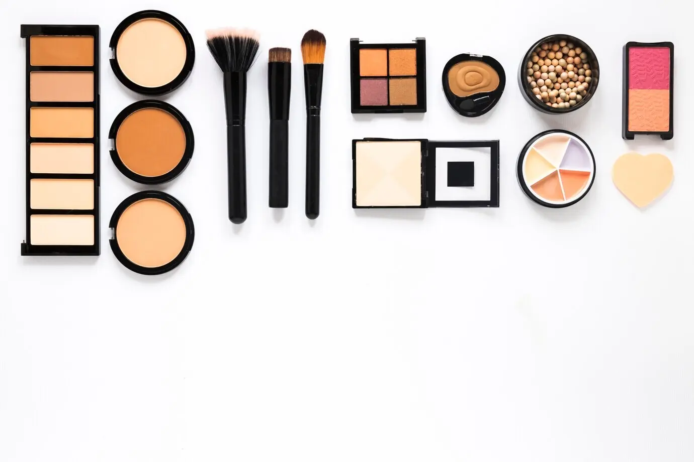Various face powders with powder brushes on a white table.