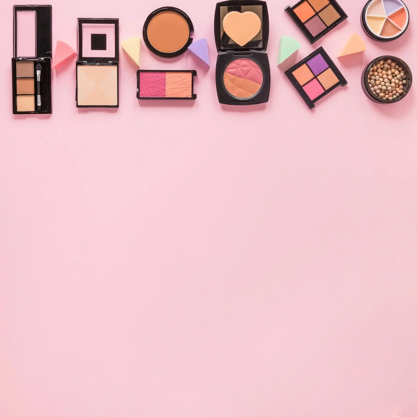 Facial powders and eye shadows on a pink table